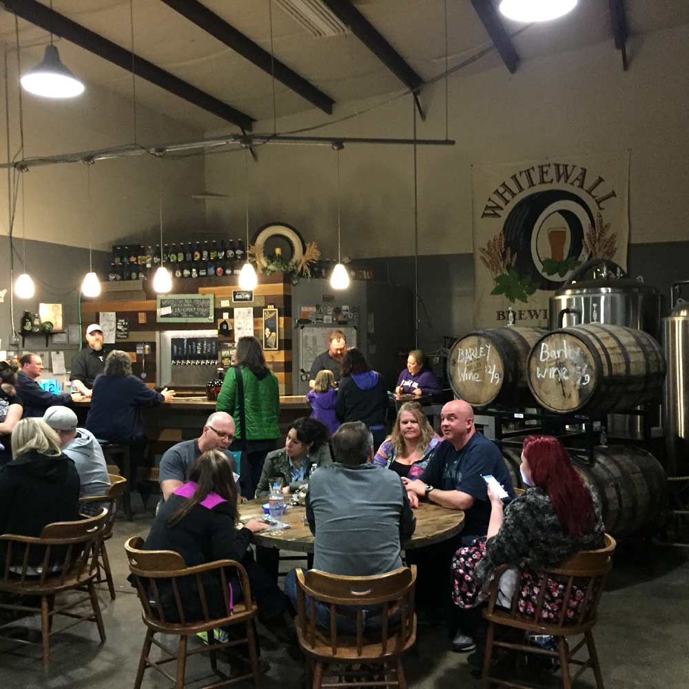 A crowd of people enjoying beers at Whitewall Brewing's taproom.