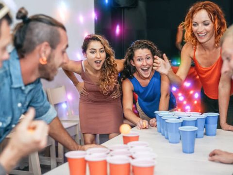 Group of friends playing beer pong - beer in college towns.