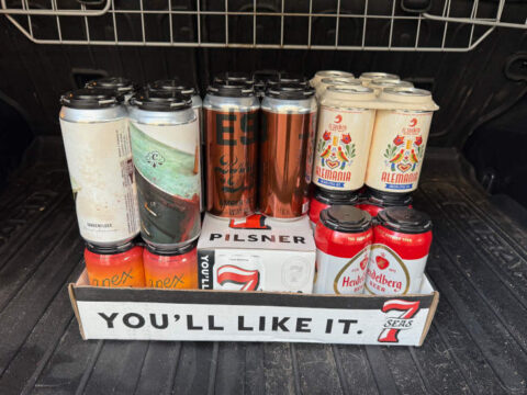 A bunch of brewery-fresh cans of beer in the back of a car.