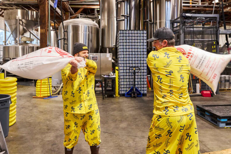 Two people in pajamas having a pillow fight in a brewery.