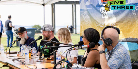 five people at a table recording a podcast