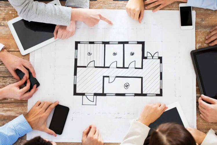 “Smart” Floor Plans: When Software Seats Guests Better Than Any Host A team discussing a digital smart floor plan layout with tablets and blueprints on a wooden table