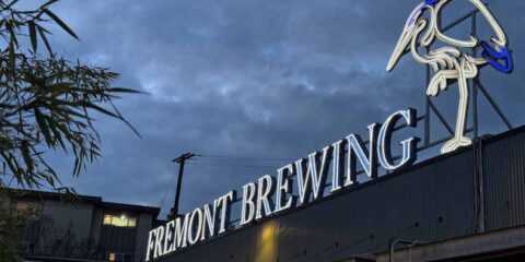 The sign on top of the building at Fremont Brewing, lit up against a cloudy sky