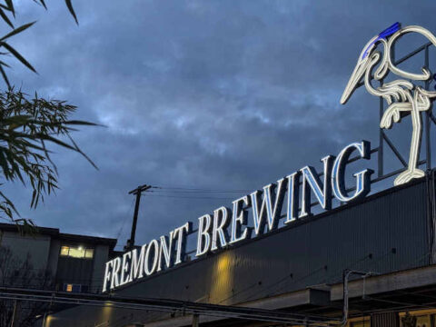 The sign on top of the building at Fremont Brewing, lit up against a cloudy sky