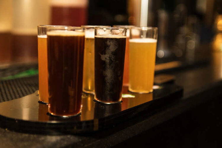 A flight of craft beers in tall glasses on a Washington casino bar counter