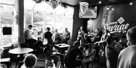 A black and white photo of a crowd in a brewery taproom