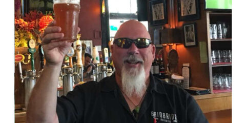 Steppin’ Up For Kenny T. Beerman in a Time of Need A man behind the bar lifting a p;int in cheers