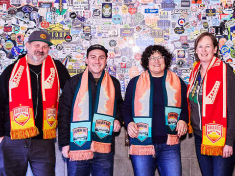 four people wearing soccer scarves