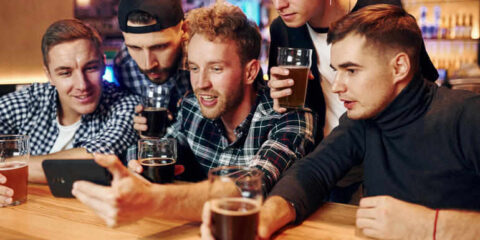 Friends at a brewery taking a phone call during a social game or event and drinking craft beer.