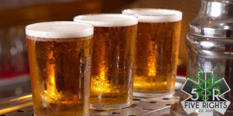 Three taster glasses of sparkling golden beer lined up beneath a tap