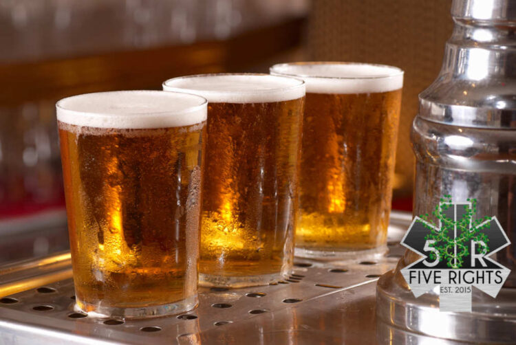 Three taster glasses of sparkling golden beer lined up beneath a tap