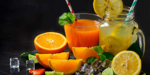 Fresh juices with mint and sliced fruit on ice in glass jars.