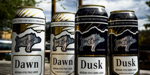 Cans of beer displayed outdoors with trees in the background