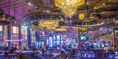 The Handshake Alternative: Using the Casino Bar as a Neutral Ground for Socializing Wide-angle view of a modern casino bar and interior with ornate circular chandeliers.