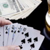Playing cards on a poker table with a glass of beer in the background.