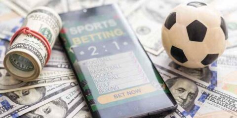 Sports Betting Ideas Every Brewer and Beer Lover Should Try Sports betting app on a phone with cash and a soccer ball, symbolizing betting trends for beer lovers.