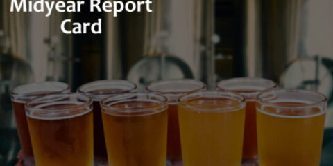 a flight of beer tasters in front of some brewery tanks