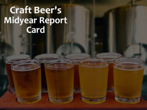 a flight of beer tasters in front of some brewery tanks