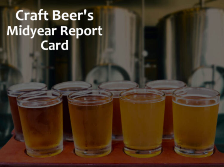a flight of beer tasters in front of some brewery tanks