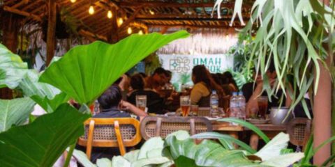 Cozy brewery taproom in Bangkok with patrons enjoying craft beer, warm lighting, and a relaxed indoor atmosphere surrounded by greenery.