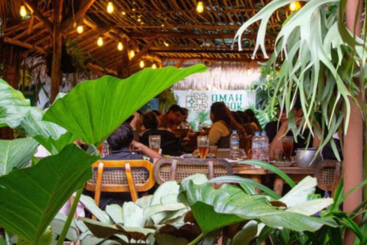 Cozy brewery taproom in Bangkok with patrons enjoying craft beer, warm lighting, and a relaxed indoor atmosphere surrounded by greenery.