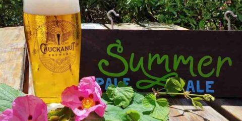 Beer Release: Chuckanut Brewery Releases its Summer Pale Ale A pint of beer on a table with some wild flowers spread around it