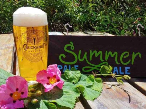 A pint of beer on a table with some wild flowers spread around it