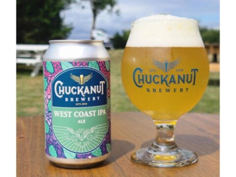 Chuckanut Brewery Colors Outside the Lines and Introduces a West Coast IPA A can of beer next to a glass of beer, sitting on a table outside with grass and trees in the background
