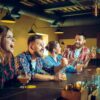 The Rise of Casual Gaming in Bars, Breweries, and Taprooms A group of friends gathered at a lively bar and taproom, laughing and cheering as they enjoyed drinks and casual games in a warm, social atmosphere.