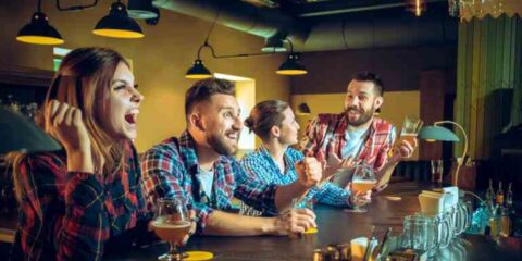 The Rise of Casual Gaming in Bars, Breweries, and Taprooms A group of friends gathered at a lively bar and taproom, laughing and cheering as they enjoyed drinks and casual games in a warm, social atmosphere.
