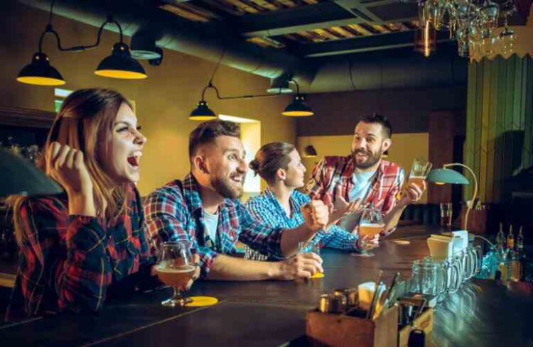 The Rise of Casual Gaming in Bars, Breweries, and Taprooms A group of friends gathered at a lively bar and taproom, laughing and cheering as they enjoyed drinks and casual games in a warm, social atmosphere.