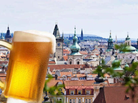 Prague Beer Guide: Best Pilsners, Craft Breweries and Local Pubs to Try A frothy glass of Czech Pilsner in front of the historic Prague skyline, celebrating the Czech beer culture, craft breweries, and historical local pubs.