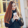 We All Need a Reliable Excuse to Leave the House A smiling woman holding a takeaway coffee outdoors, suggesting a simple reason to step outside on a cold day.