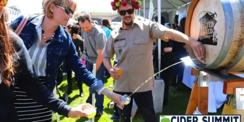 TICKET GIVEAWAY – Cider Summit Seattle Returns for a 15th Delicious Year A woman filling a glass of cider straight from the barrel