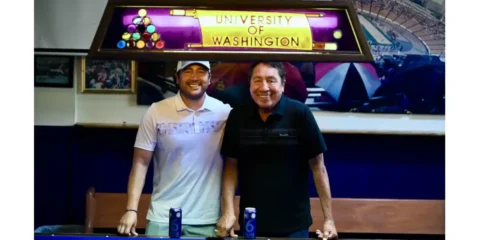 Two men standing in a bar and leaning on a pool table