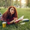 How College Students Can Balance Studying, Hobbies, And Social Life Without Burning Out College student girl relaxing in a garden with a book while balancing study, hobbies, and social life.