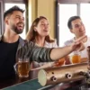 What Is a Parlay Bet: A Beer Lover’s Game Day Guide Friends enjoying beer and watching football at a sports bar while discussing parlay bets on game day.