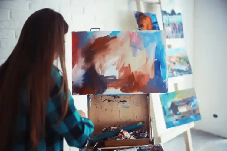 College student painting on a canvas in an art studio, illustrating how hobbies and social activities support student life and personal growth.