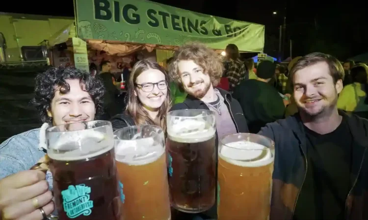 Four people enjoying beers at a lively beer festival
