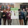 2 Towns Ciderhouse Launches Hunger Action Month Campaign to Benefit Oregon Food Bank A group of people standing around a Donation sign