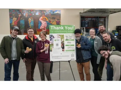 2 Towns Ciderhouse Launches Hunger Action Month Campaign to Benefit Oregon Food Bank A group of people standing around a Donation sign