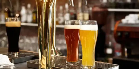 Multiple beers being served from a draft system at a bar, highlighting the challenges of pouring non-alcoholic beer on draft.