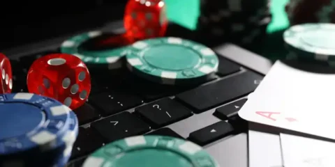 Live dealer casino game with poker chips, dice, playing cards, and computer keyboard representing RNG slots and casino games.