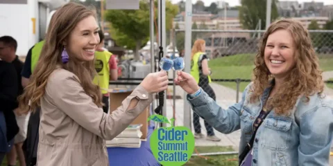 Two friends enjoying cider at a festival