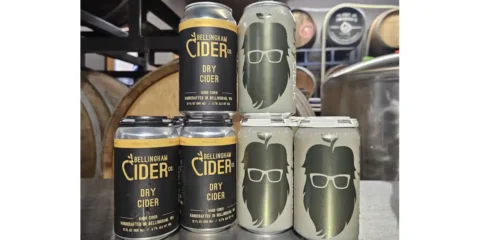 Bellingham Cider Company is Taking Over Lost Giants Cider Company Cans of cider from stacked up with barrels in the background
