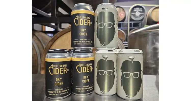 Cans of cider from stacked up with barrels in the background