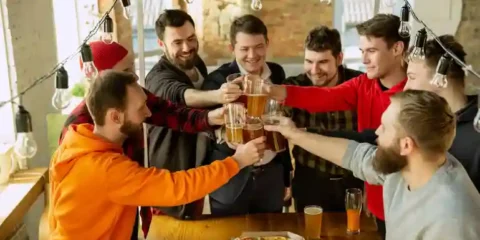 Friends raising beer glasses together at a brewery club gathering.