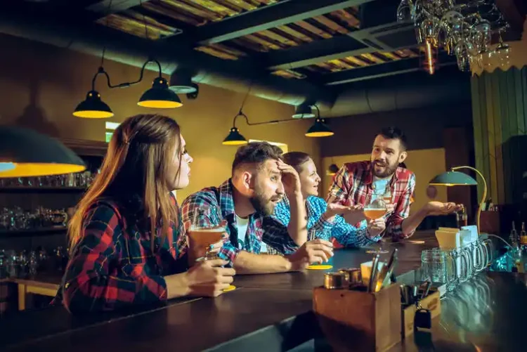 Friends enjoying beer together during a taproom game night with glasses in hand.
