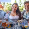 This Weekend, Join Ounces Taproom for Three Days of Oktoberfest Fun Three people in Oktoberfest garb with mugs of beer