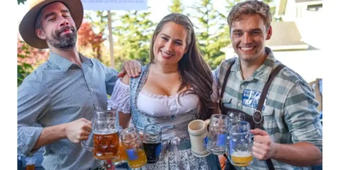 This Weekend, Join Ounces Taproom for Three Days of Oktoberfest Fun Three people in Oktoberfest garb with mugs of beer